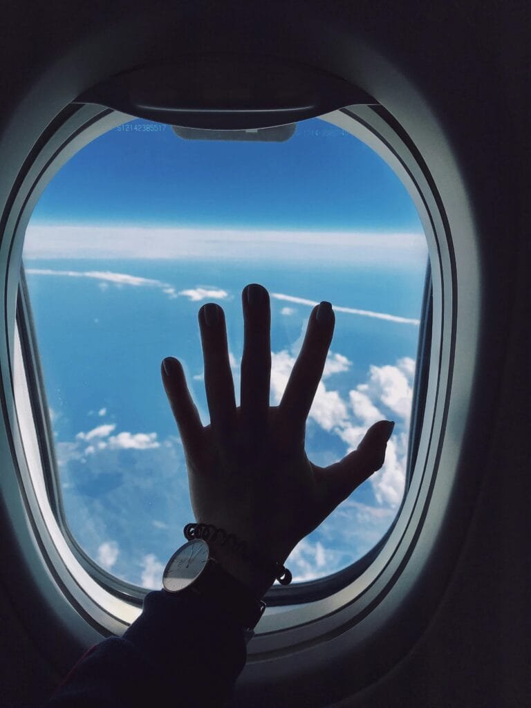 Image of a plane window and a hand – indicating an adventurous spirit.