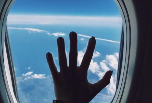 Image of a plane window and a hand – indicating an adventurous spirit.