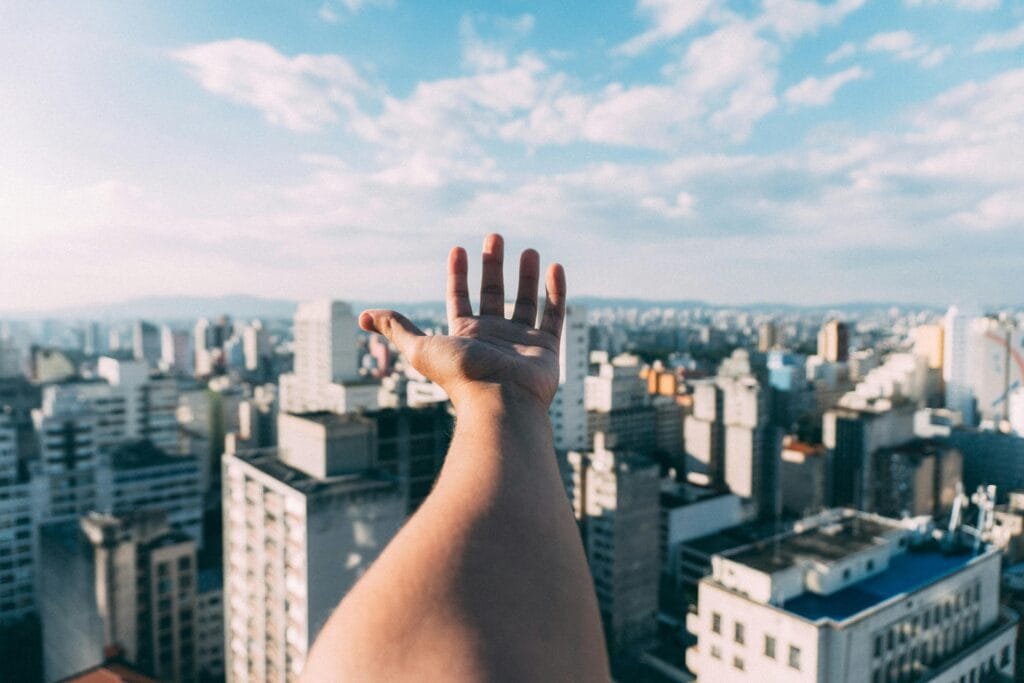 Master your personal finance to conquer the world. Hand outstretched with skyscrapers in the background.