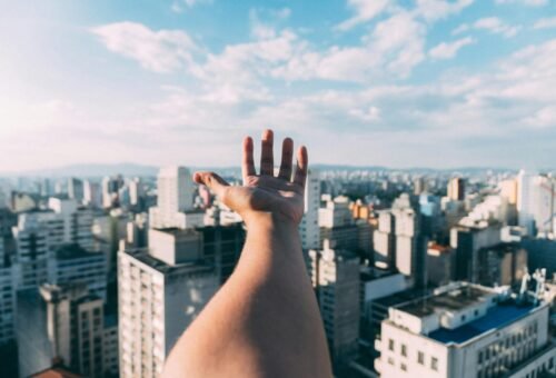 Master your personal finance to conquer the world. Hand outstretched with skyscrapers in the background.