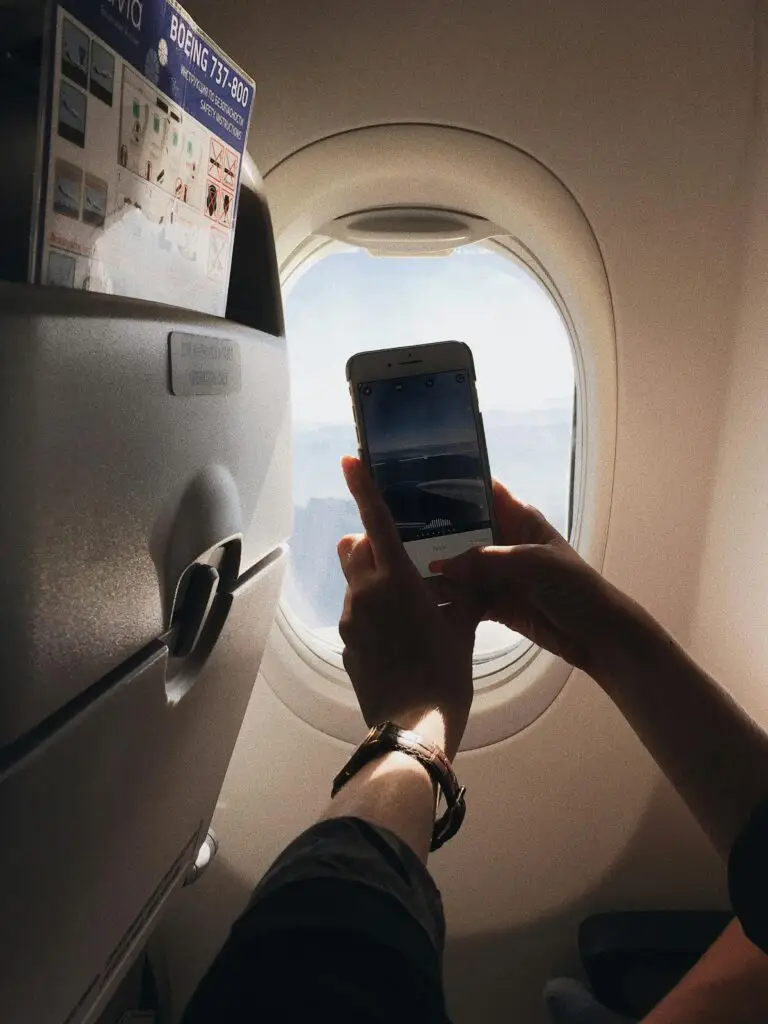 A phone on a plane displaying the best travel apps