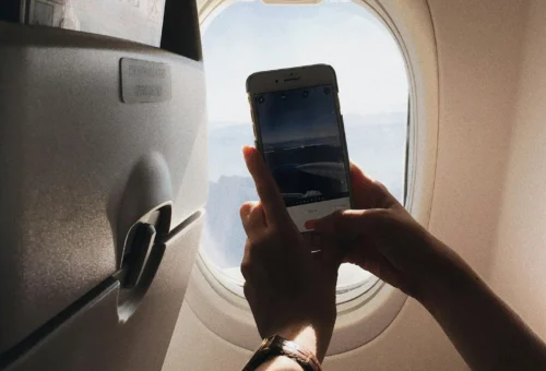 A phone on a plane displaying the best travel apps